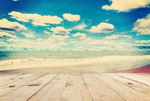 Wood table sand beach sea and in sky clouds with vintage tone. photo