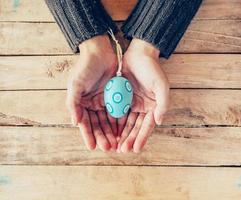 Close up hand woman holding and person easter eggs on wood table background. photo