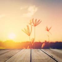 Abstract blurred wild flower sunset and wood table with vintage tone. photo