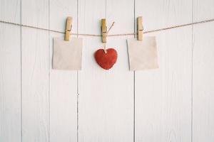 Two blank old paper and red heart hanging. On white wooden background with vintage style. photo