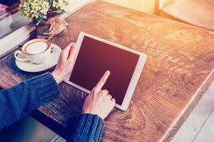 Close up hand woman using tablet in coffee shop with vintage tone. photo