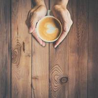 man hand holding hot cup of coffee, with heart shape photo