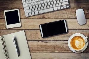 Office table with coffee cup, computer, phone, notebook and pen. View from above with copy space photo