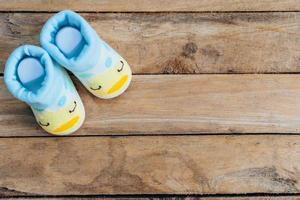 Baby shoes on wooden background with space photo