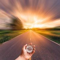 mano hombre participación Brújula en borroso la carretera con cielo puesta de sol. foto