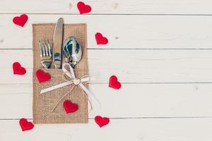 mesa conjunto para celebracion San Valentín día. de madera mesa sitio ajuste y cubiertos con rojo corazón para enamorado día. foto