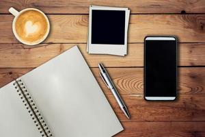 Mobile phone, notebook pen, photo frame and coffee cup on office wooden table with copy space.