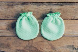 baby gloves on wooden background with space photo