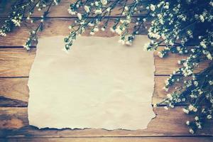 Flowers and old paper on wood texture background with copyspace. Vintage style. photo