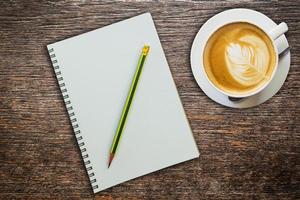 above coffee and notebook with pencil on wood texture photo