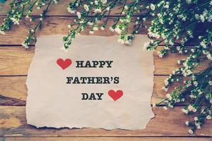 Happy Fathers day on brown paper with white flower on wooden board photo