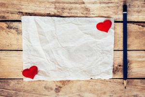 antiguo papel y rojo corazón con lápiz en madera antecedentes para enamorado saludo tarjeta. foto