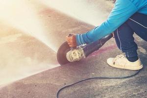 Close up hand man cutting concrete floor with machine. photo