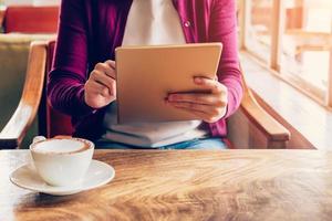 Woman hands using and holding  computer tablet in coffee shop with vintage toned. photo