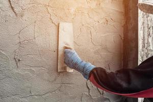 plasterer concrete worker at wall of home construction building photo