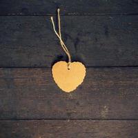 Blank brown tag heart shape on old wood background with space.