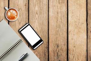 smartphone coffee cup and notebook on wooden background with space. photo