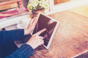 Close up hand woman using tablet in coffee shop with vintage tone. photo