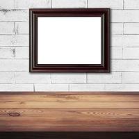 frame picture on white brick wall and wood table background texture with space photo