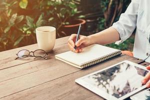 Young business woman hand with pencil writing on notebook. Woman hand with pencil writing on notebook and working at coffee shop. photo