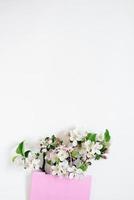 Apple tree flowers in a shopping bag on a white background with copy space. Top view and flat lay. The concept of spring discounts in stores. photo