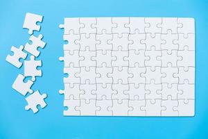 Unfinished white jigsaw puzzle pieces on blue background, The last piece of jigsaw puzzle, Copy space. photo