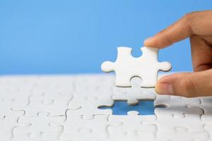 Hand put the last piece of jigsaw puzzle to complete the mission. Completing final task, missing jigsaw puzzle pieces and business concept with a puzzle piece missing. photo