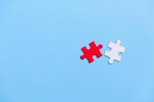 White and red jigsaw puzzle on a blue background. Copy space for text, top view, close up. photo
