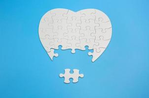 White heart shaped jigsaw puzzle on blue background with copy space. Business strategy teamwork and problem solving concept. photo