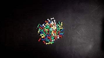 multicolored thumbtacks on a black background photo