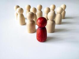 Red wooden doll leading the rest of wooden figure. Leadership and followers concept. photo