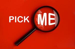 Pick me text on red background with magnifying glass. Hiring concept photo