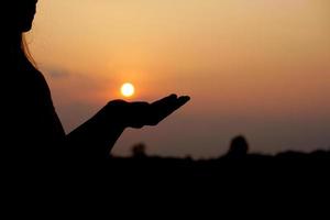 silueta de humano mano elevado a hacer un desear, puesta de sol antecedentes foto