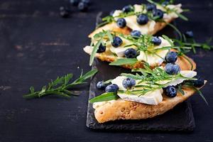 Bruschetta. Toast crostini with fresh berries blueberry and honey, brie cheese, arugula. Italian cuisine photo