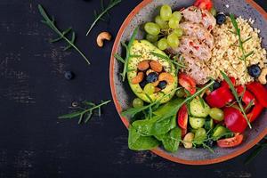 Buddha bowl dish with meatloaf, bulgur, avocado, sweet pepper, tomato, cucumber, berries and nuts. Detox and healthy superfoods bowl concept. Overhead, top view, flat lay photo