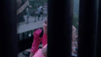 A Glamour princess with the crown and pink dress standing between the pillar in her royal palace video