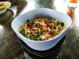 noodle soup in a white bowl on a wooden table photo