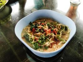 noodle soup in a white bowl on a wooden table photo
