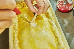 cocinero cortes agujeros en un soufflé hecho desde papas, calabacines, coliflor y amarillo queso foto