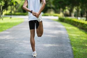 Athletes sport man runner wearing white sportswear to stretching foot and legs and warm up before practicing on a running track at a stadium park. Runner sport concept. photo