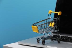 Shopping Online Concept Mini Shopping Cart On Laptop photo