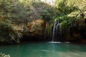 Long exposure waterfall during the day. green forest and rocky mountain. summer time. crystal clear blue water. beautiful waterfall with blue lake in the forest. photo