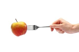 hembra mano sostiene un metal tenedor con Fresco manzana en un blanco antecedentes. sano orgánico comida para dieta concepto foto