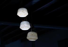 3 white pendant lamps on a black background to stand out and the beauty of the light. Soft and selective focus. photo