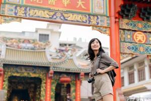 Young Asian woman backpack traveler enjoying China town street food market in Bangkok, Thailand. Traveler checking out side streets. photo