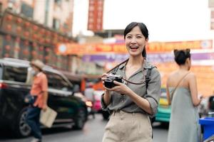 Young Asian woman backpack traveler enjoying China town street food market in Bangkok, Thailand. Traveler checking out side streets. photo