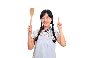 Portrait of beautiful young asian woman smile in denim dress with spatula on white background photo