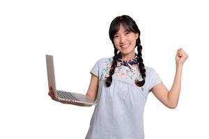 Portrait of beautiful happy young freelance asian woman in denim dress using laptop work with success on white background photo