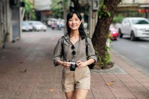 Young Asian woman backpack traveler using digital compact camera, enjoying street cultural local place and smile. photo