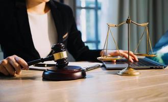 Justice and law concept.Male judge in a courtroom with the gavel, working with, computer and docking keyboard, eyeglasses, on table in morning light photo